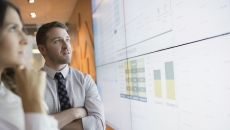 Two people standing beside a board and looking at it
