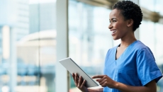 Healthcare provider holding a tablet while looking out a window
