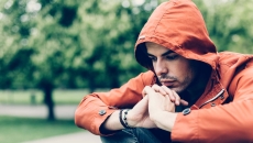 Person sitting in a park while wearing an orange sweater with a hood Person sitting in a park while wearing an orange sweater with a hood