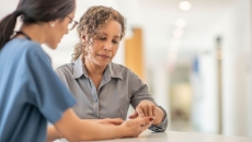 A healthcare provider speaking to an individual in a clinical setting A healthcare provider speaking to an individual in a clinical setting