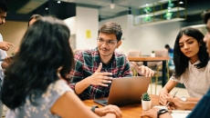 Group of individuals sitting around a table talking Group of individuals sitting around a table talking
