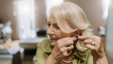 Person putting a hearing aid in their ear Person putting a hearing aid in their ear