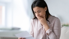 Person with their mouth covered looking at a piece of paper Person with their mouth covered looking at a piece of paper