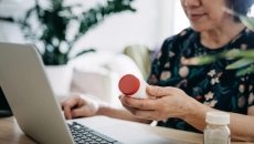 Person on a computer holding medication Person on a computer holding medication