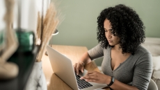 Person sitting at a desk looking at a computer Person sitting at a desk looking at a computer