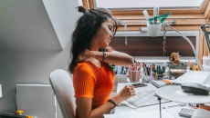 Person rubbing their neck while sitting at a desk Person rubbing their neck while sitting at a desk