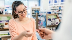 Person handing a piece of paper to a pharmacist