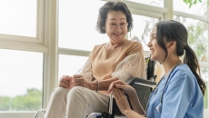 A caregiver sitting beside a senior patient in a wheelchair