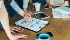 A close-up of a group of workers looking at a paper with financial charts