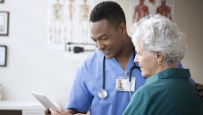 A doctor and a patient looking at information on a tablet.