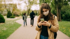 A person wearing mask is typing on their phone