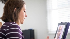 A woman talking to a provider though a video chat on a tablet. A woman talking to a provider though a video chat on a tablet.