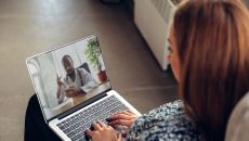A woman talking to a doctor via telehealth using her laptop