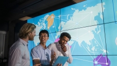 Three people standing in front of a world map