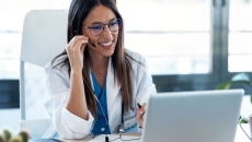 Healthcare stakeholder sitting at a desk looking at a computer with a headset on