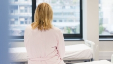 A woman sitting with her back to the camera on a hospital bed