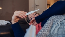 A sick woman looking a thermometer A sick woman looking a thermometer