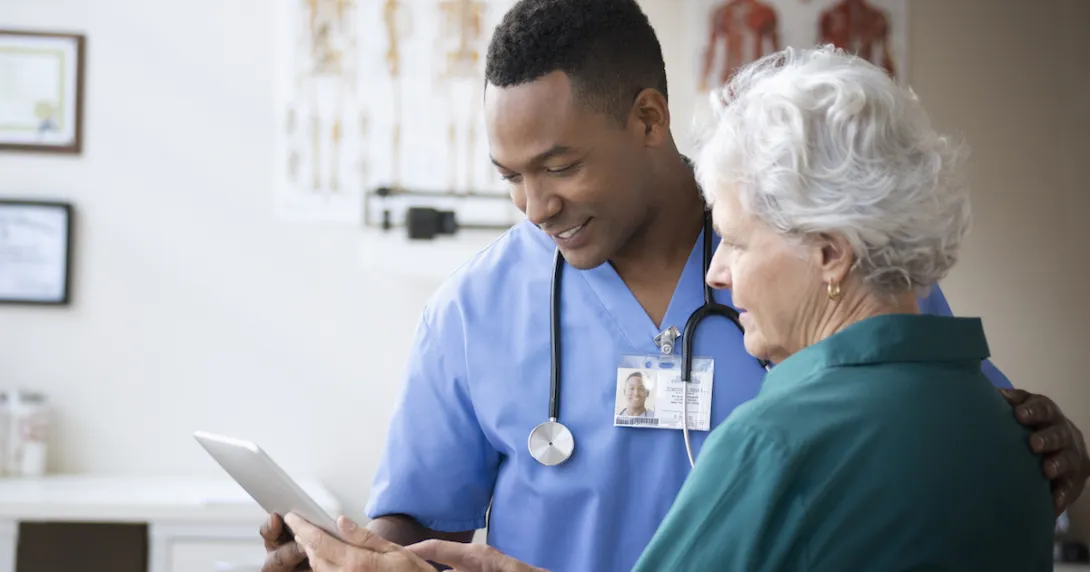 Healthcare provider showing a tablet to a patient Healthcare provider showing a tablet to a patient