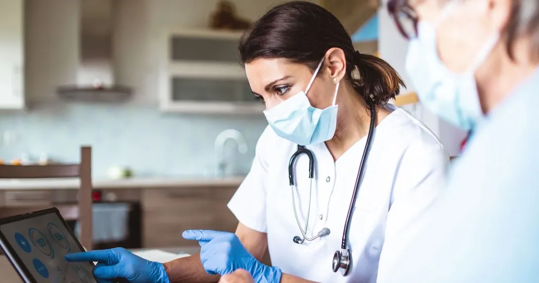 Healthcare providers in lab coats wearing a mask and stethoscope and looking at a screen Healthcare providers in lab coats wearing a mask and stethoscope and looking at a screen