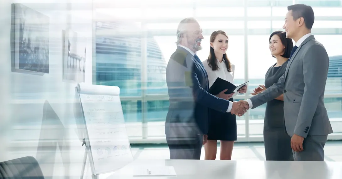 Two people shaking hands while two others are watching Two people shaking hands while two others are watching