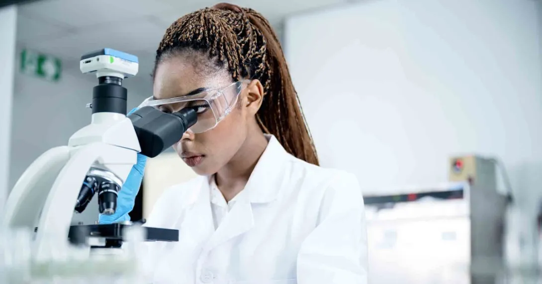 Scientist in a lab looking through a microscope