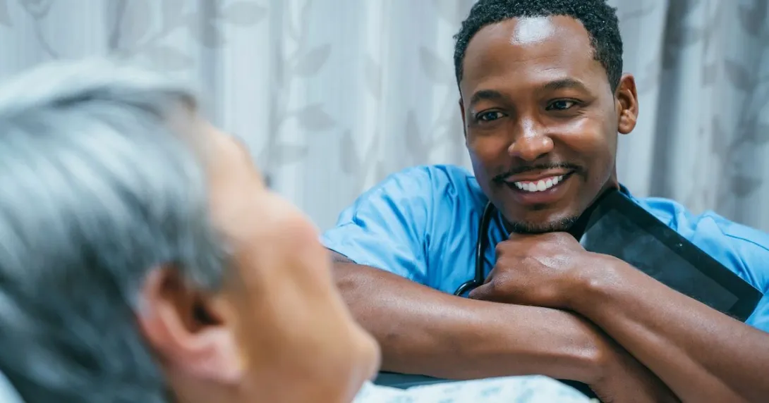 Healthcare provider sitting at a patient's bedside Healthcare provider sitting at a patient's bedside