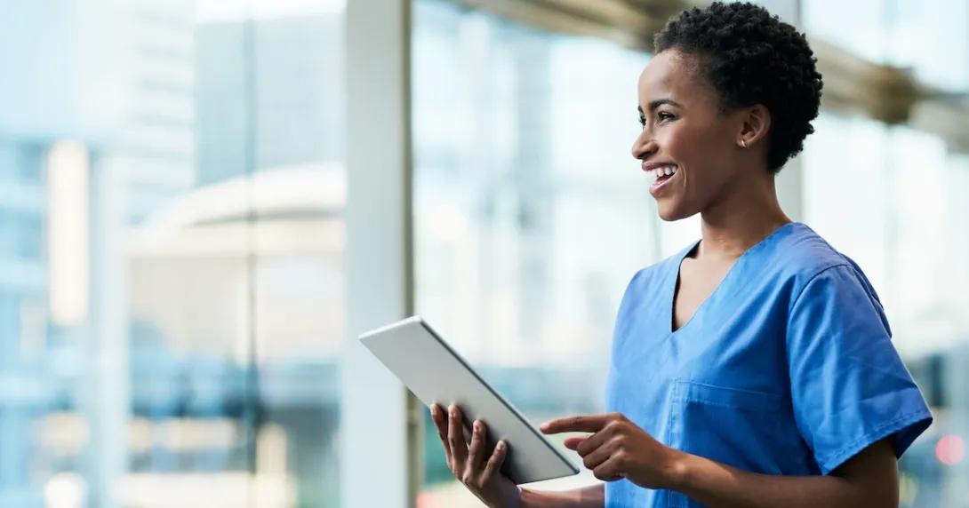 Healthcare provider holding a tablet while looking out a window
