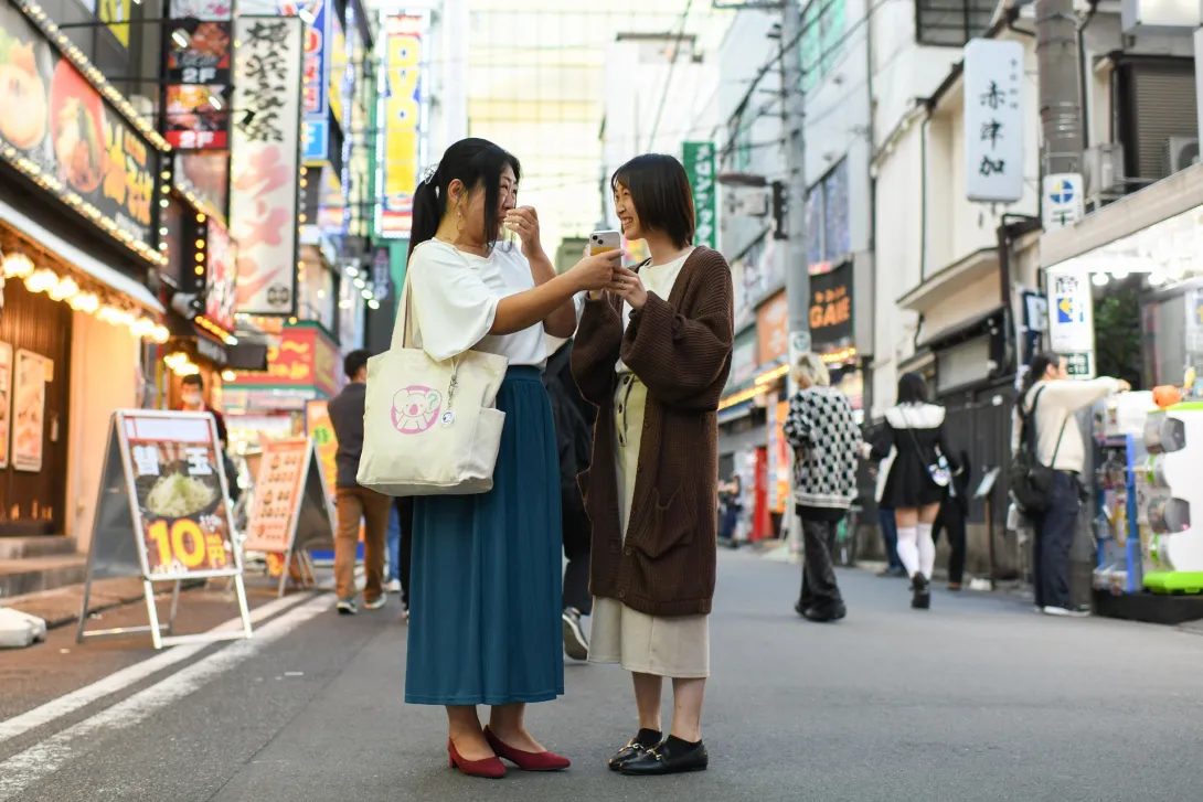 Two persons in the middle of the street talking to each other using a mobile translator app