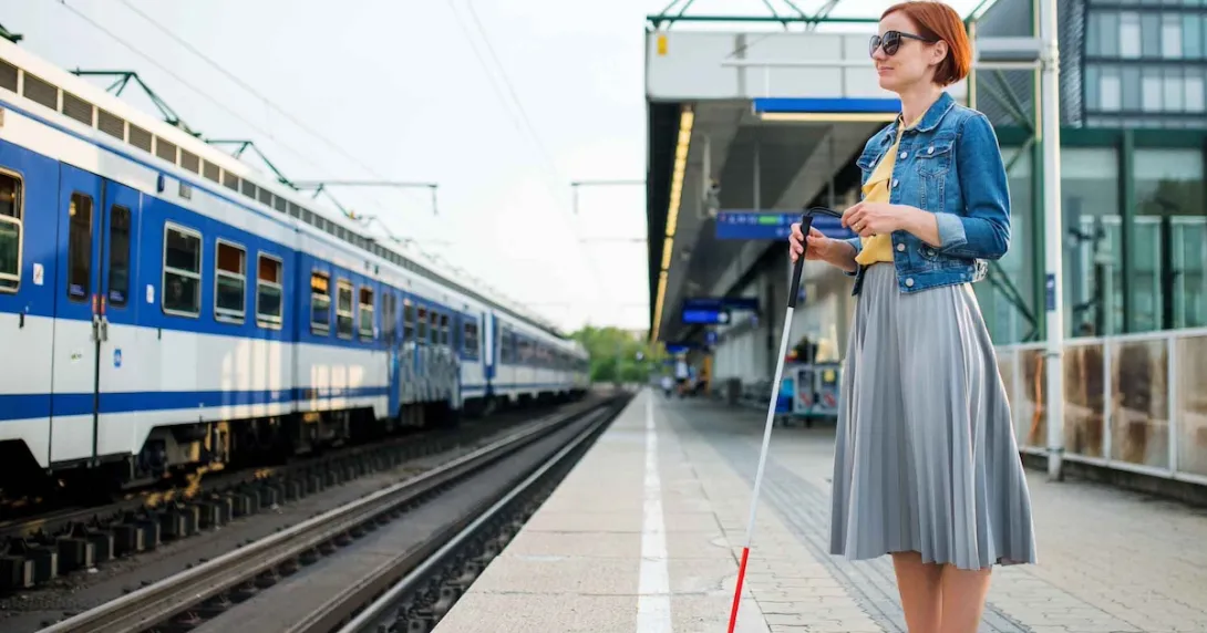 Blind person standing on a train station platform