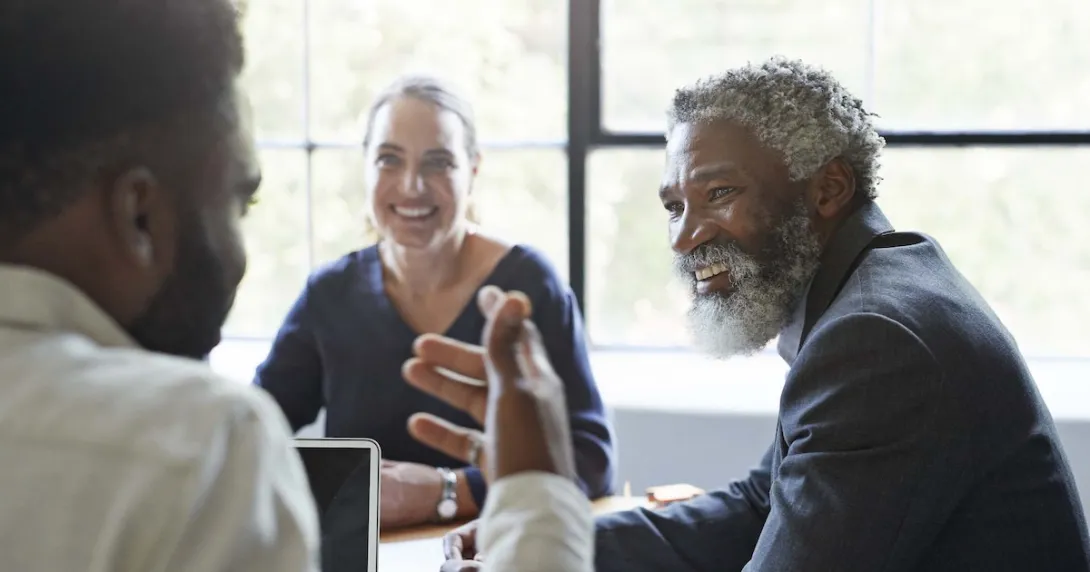 Three business people sitting around a table and talking