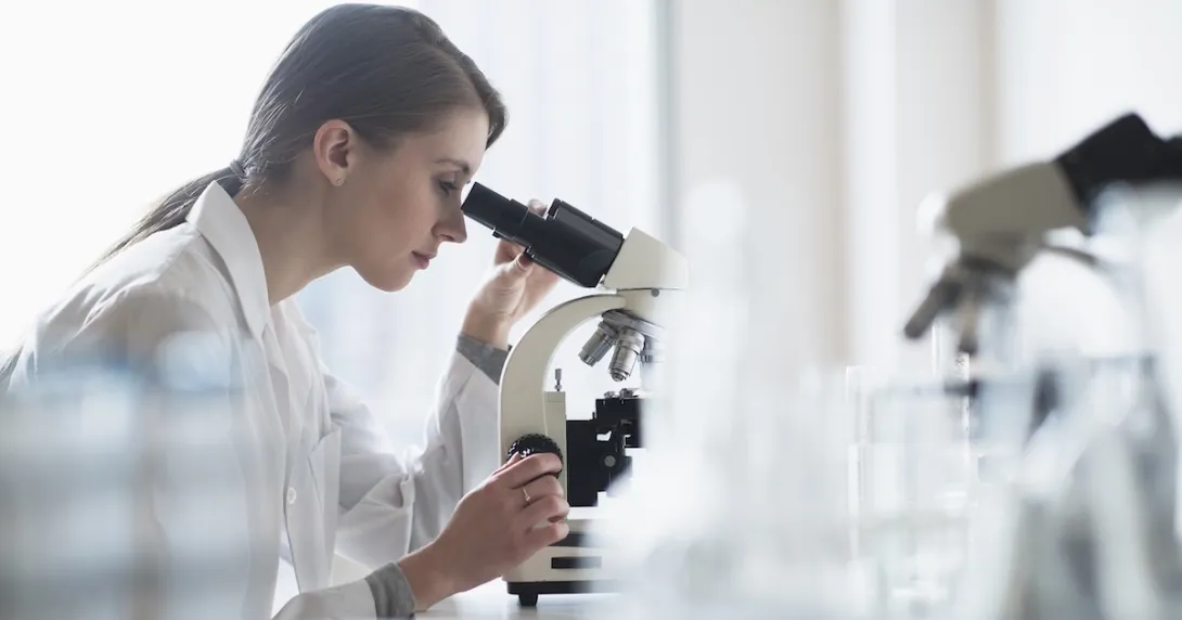 Technician looking into a microscope