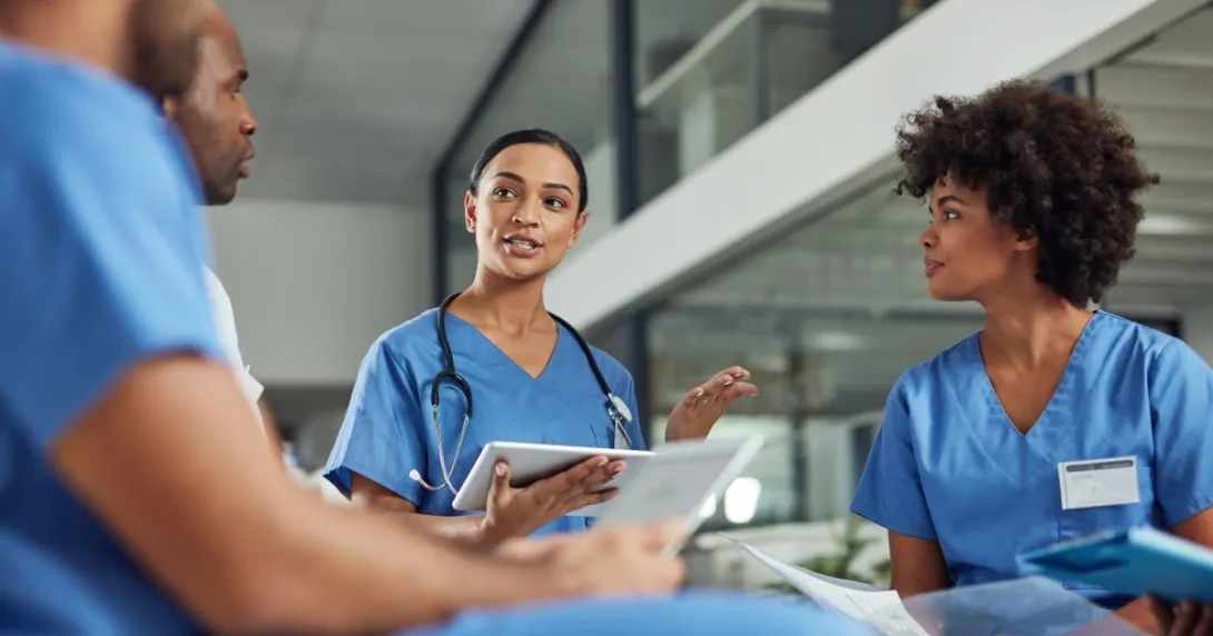 Four people in nursing uniforms, one wearing stethoscope