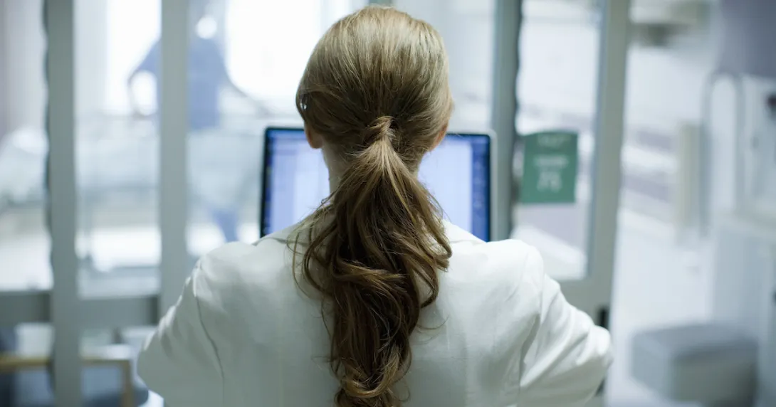 Healthcare provider with their back turned while looking at a computer