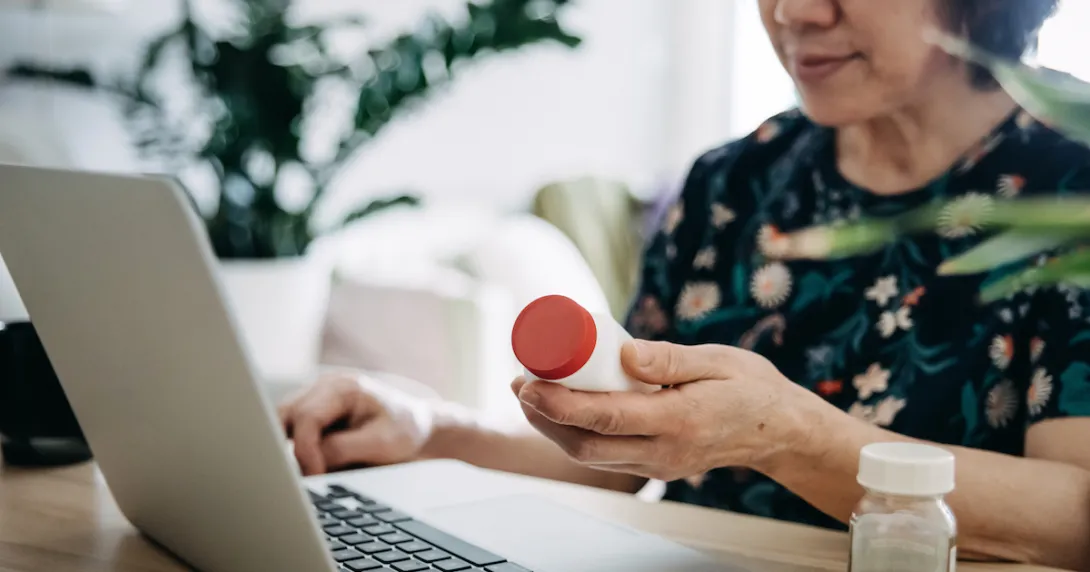 Person on a computer holding medication