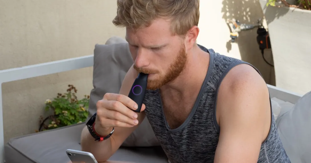 A man using the Lumen device while looking at his phone.