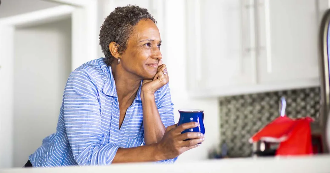 Person leaning against a counter holding a coffee cup
