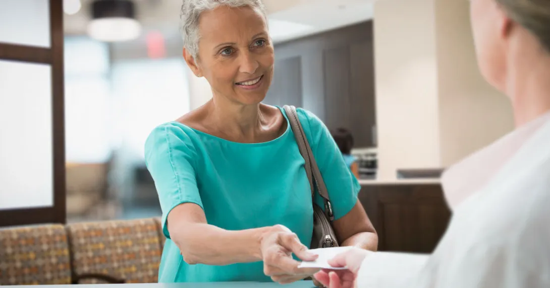 Person handing a piece of paper to a healthcare professional
