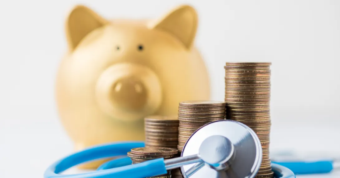 A piggy bank next to stethoscope and pile of coins