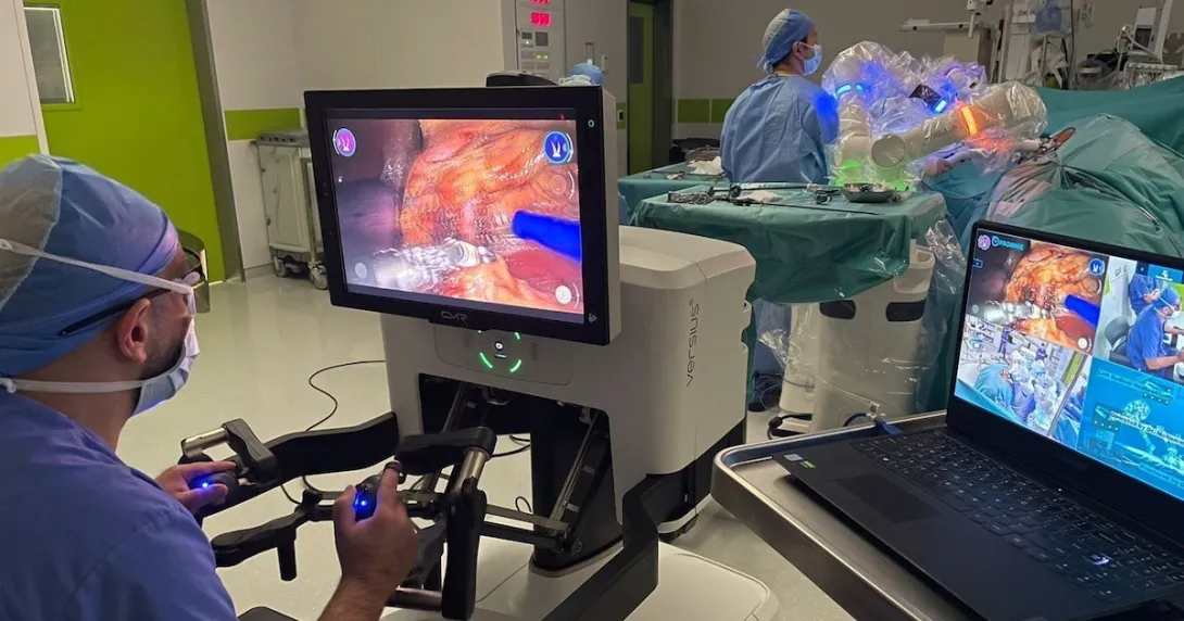 A surgeon operating while other clinicians follow along on a laptop using Proximie's platform