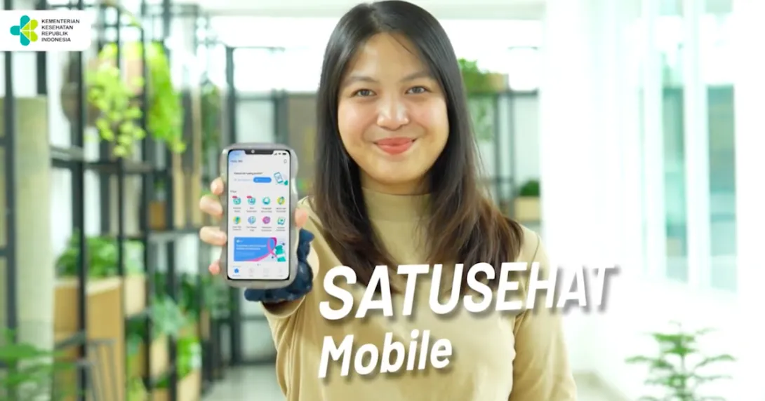 A person holding a mobile phone showing the Satusehat app
