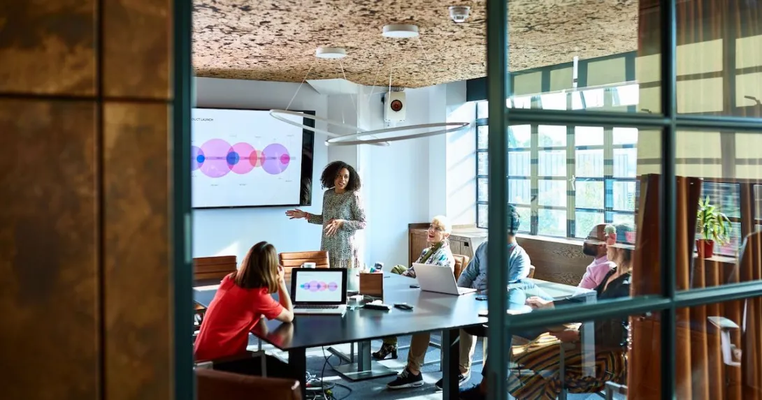 A woman presents in front of a group of colleagues