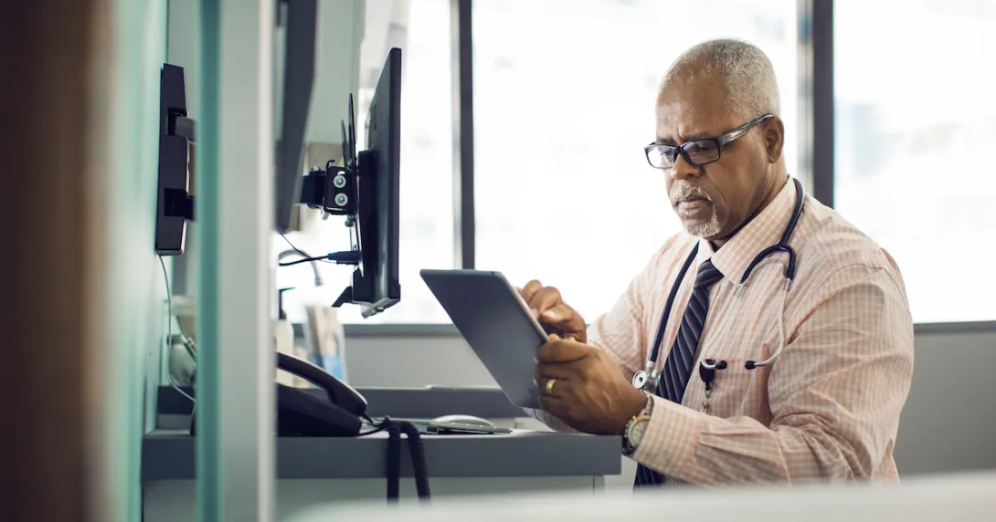 A doctor sitting at a desk using a tablet