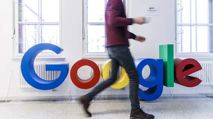 A person walking past a Google sign in an office