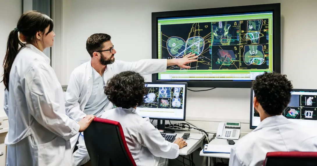 A group of doctors discussing a patient's test results on a large monitor in an office.