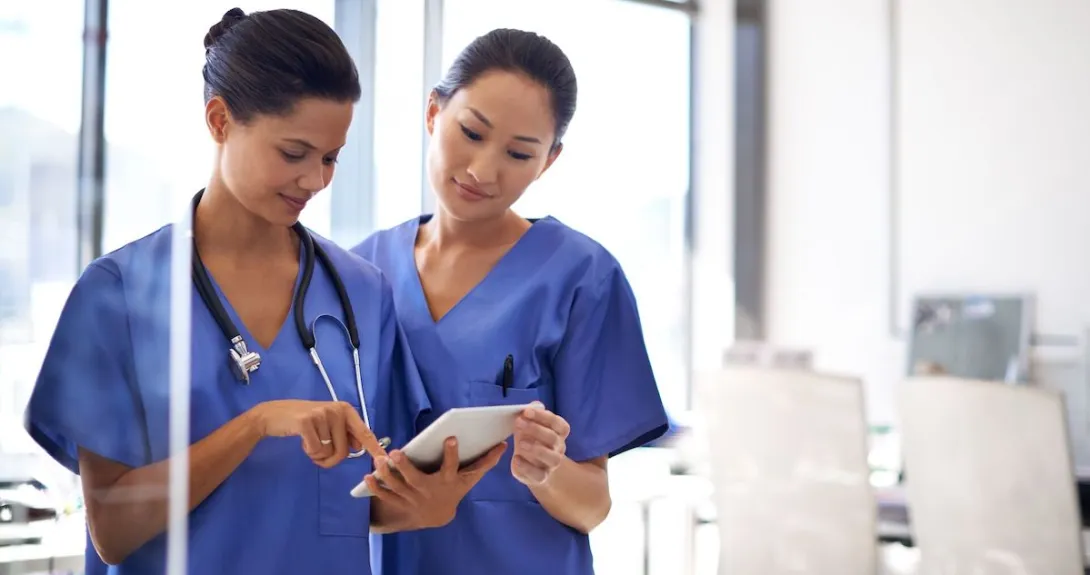 Two nurses using a tablet to review medical records.