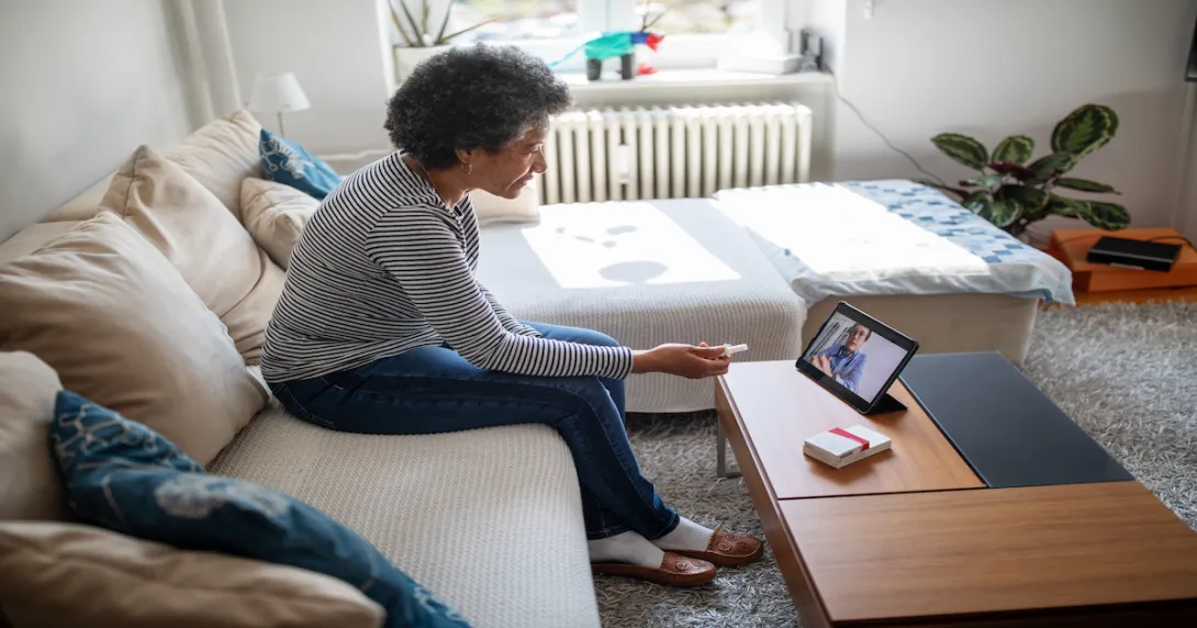 An older woman talking to a provider using a tablet.