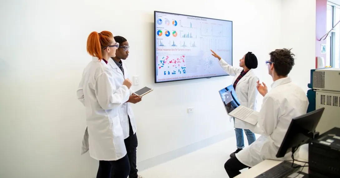A team of researchers looking at charts on a monitor