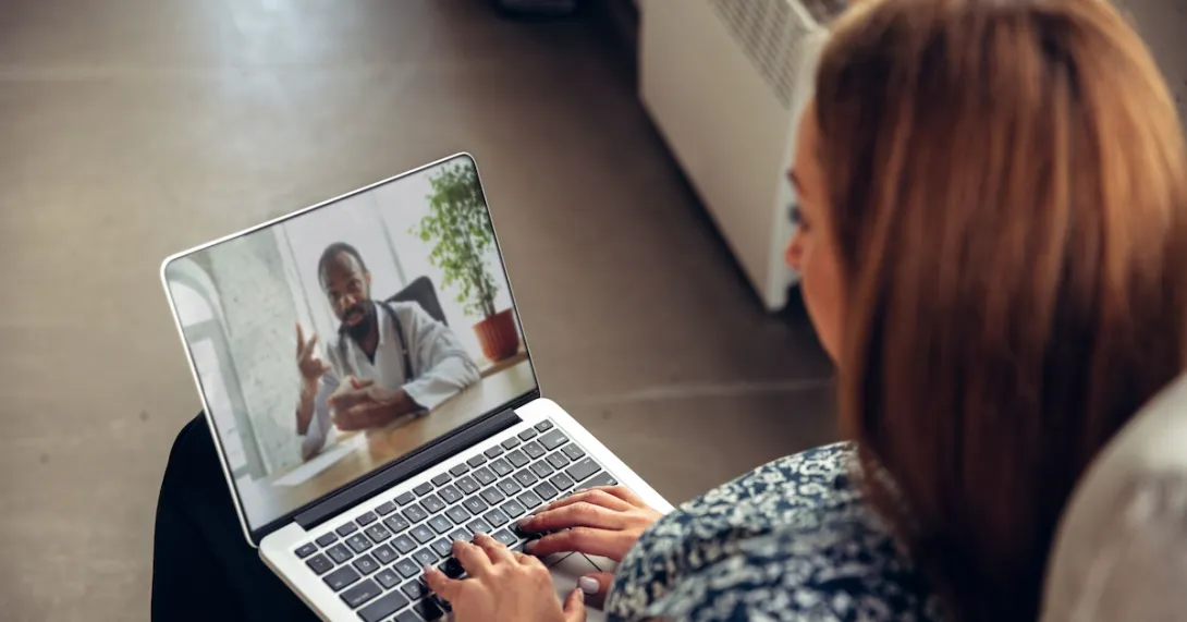 A person talking to a provider through a video chat on a laptop