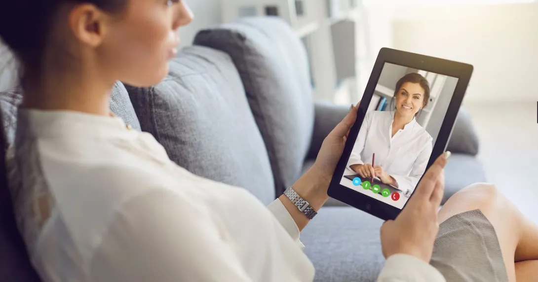 Person sitting on their couch speaking to a healthcare professional on a tablet