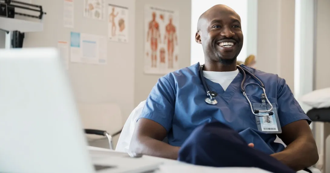 Healthcare provider sitting at a desk while wearing scrubs